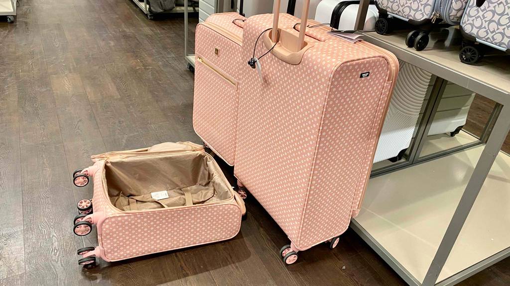 Im Test: 3-teiliges Kofferset in Rosa befindet sich in einem Verkaufsbereich, ein kleiner Koffer liegt geöffnet auf einem braunen Boden.