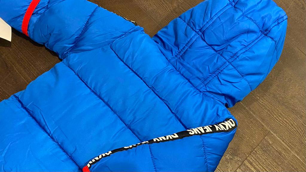 Im Test: Kinder Schneeanzug von DKNY in blau liegt mit der Rückseite nach oben auf Holzboden.