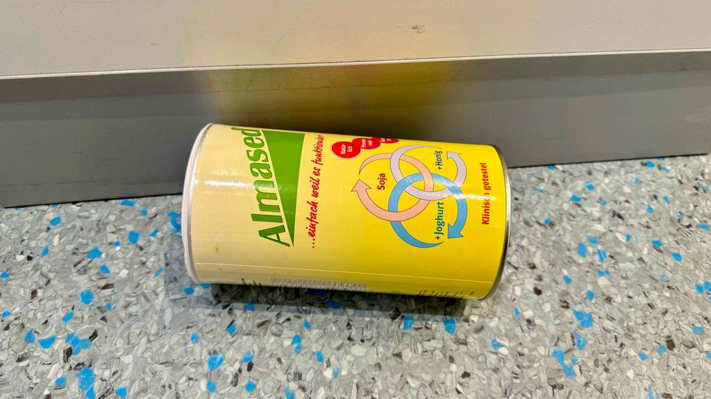 Im Test: Eine Dose Almased liegt quer auf einem gesprenkelten Boden.