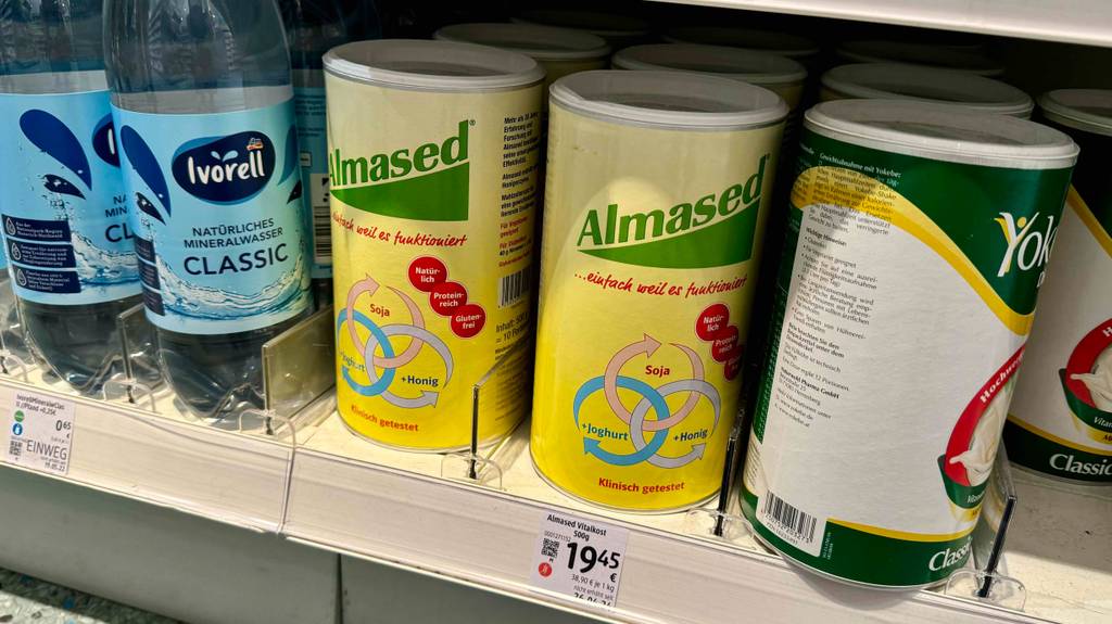 Im Test: Mehrere Dosen Almased stehen zwischen Wasser und einem anderen Produkt in einem Verkaufsregal.