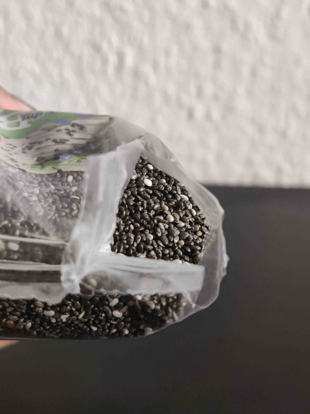 Im Test: Nahaufnahme einer aufgerissenen Packung Chia-Samen mit Fokus auf die Samen.