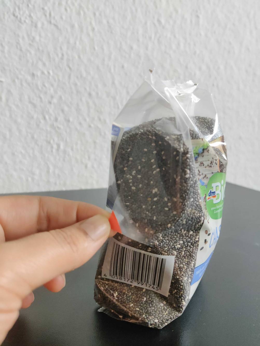 Eine Hand hält eine rote Ecke einer Packung getesteter Chia-Samen.