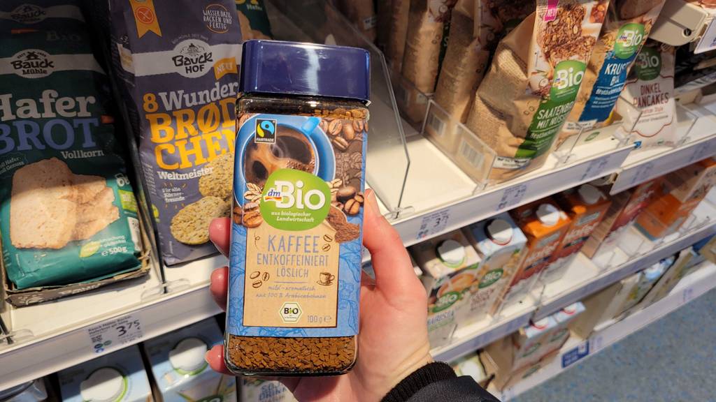 Im Test: Eine Hand hält eine Packung Bio-Kaffee entkoffeiniert vor einem Regal.
