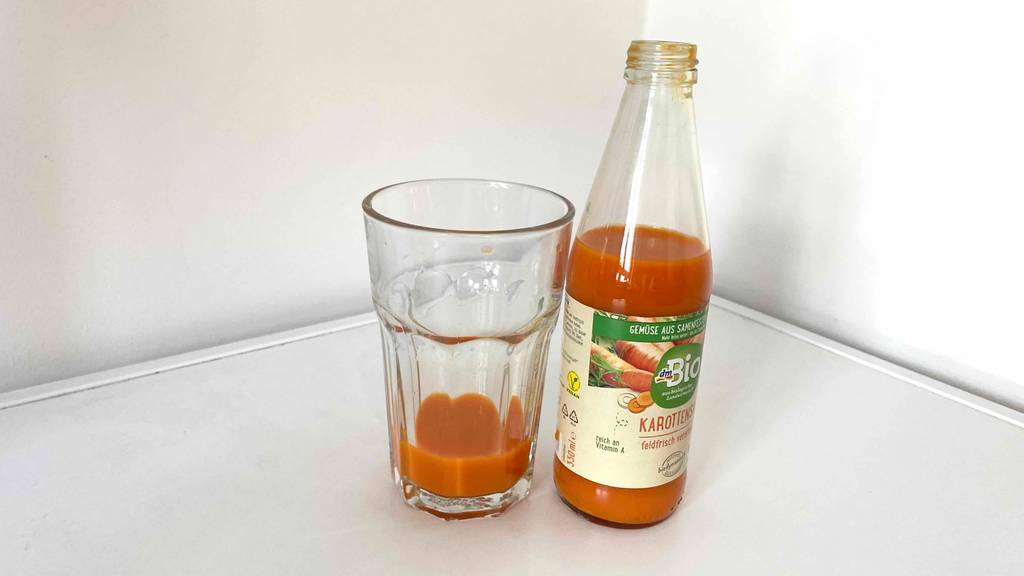 Ansicht eines getesteten Karottensaftes von dm, der neben einem Glas mit oranger Flüssigkeit steht.