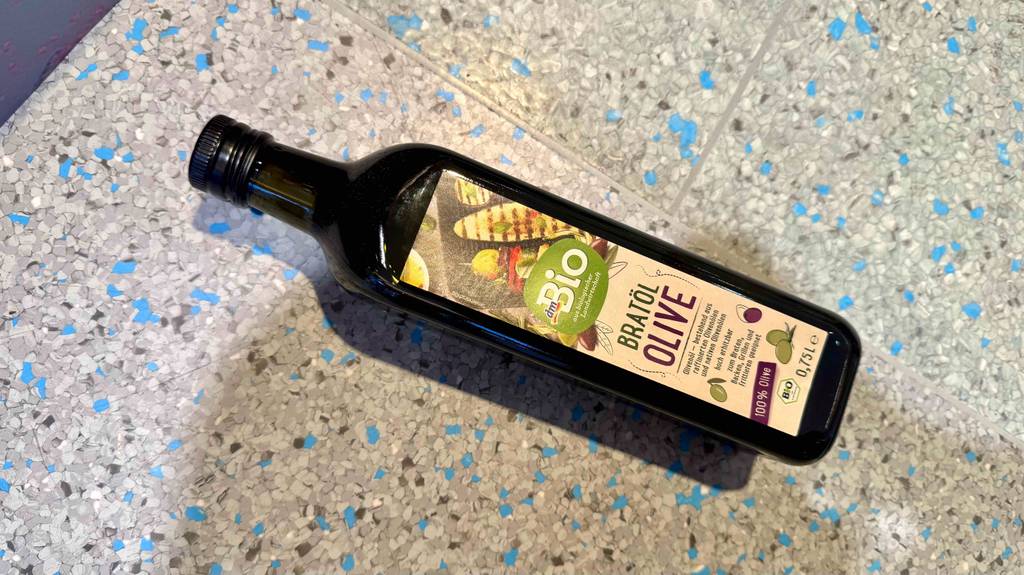 Ein getestetes Olivenöl zum Braten in einer 750-ml-Flasche liegt auf einem Linoleumbelag.