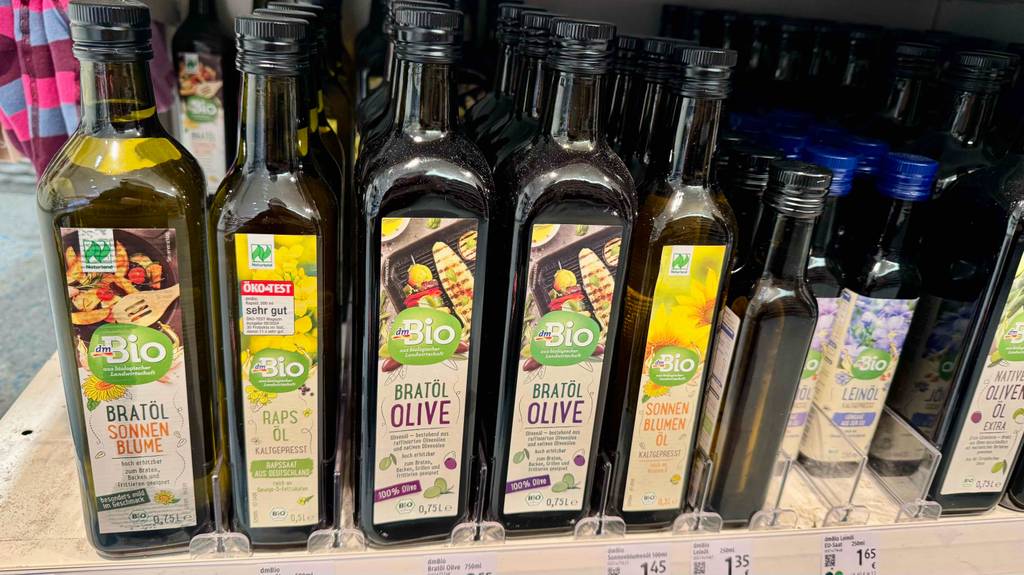Getestet: Olivenöl zum Braten in 750-ml-Flaschen steht in einem Verkaufsregal neben mehreren Flaschen mit verschiedenen Ölsorten.