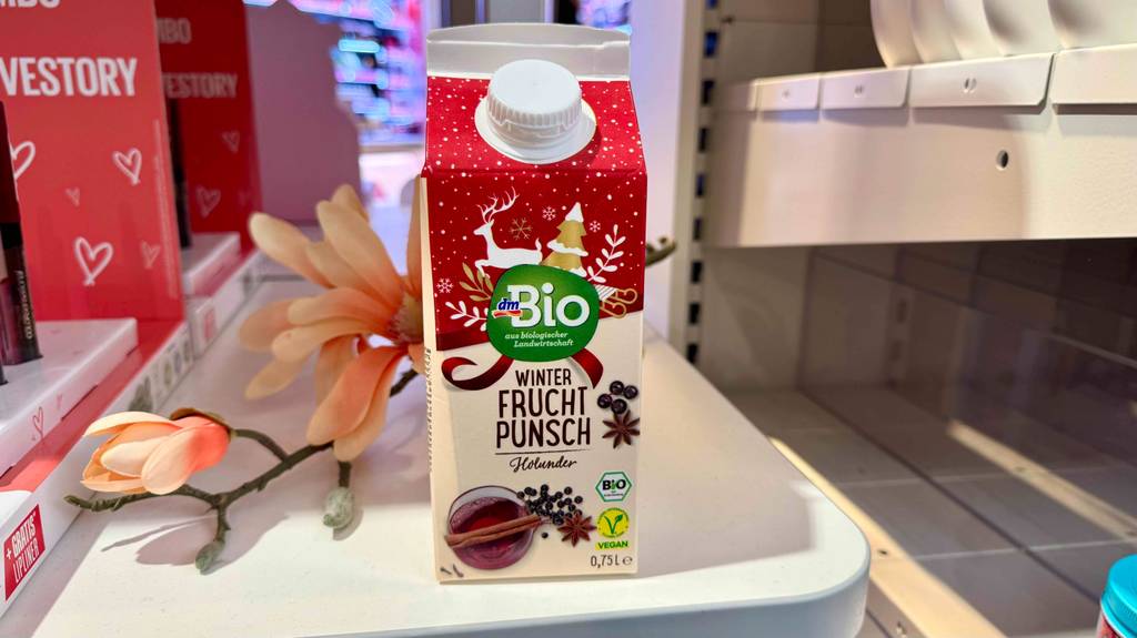Ein Tetrapak getesteter Punsch steht vor einer Blume.