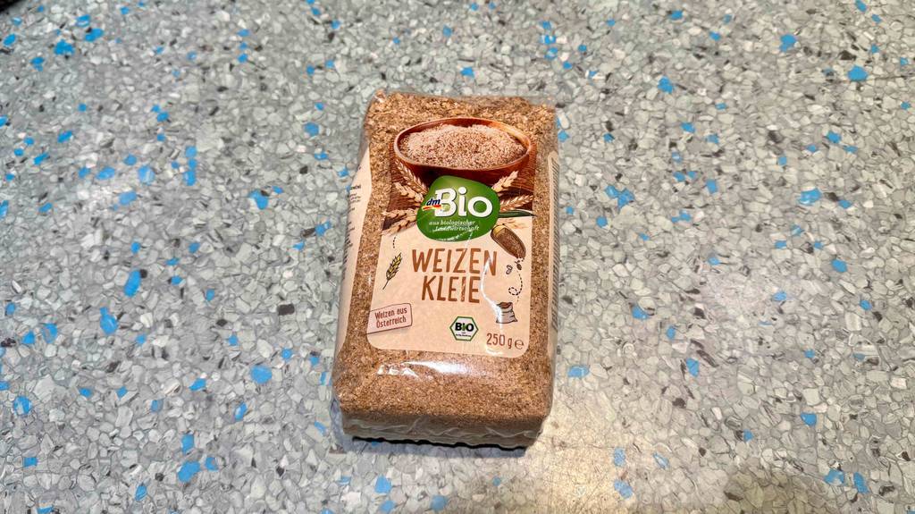 Eine Packung Weizenkleie liegt getestet auf einem gesprenkelten Boden.