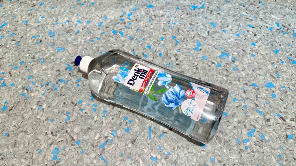 Getestetes Bügelwasser in der Sprühflasche liegt auf dem Boden.