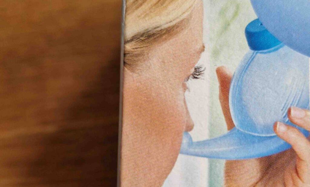 Nasenspülsalz im Test: Detailansicht einer Verpackung, auf der eine Frau mit einem Inhalator für die Therapie mit Nasenspülsalz zu sehen ist.