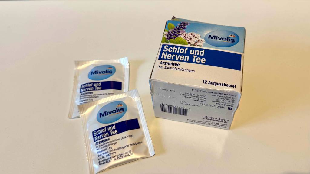 Schlaf-und-Nerventee-Test: Die Kartonverpackung hat unten Informationen zum Inhalt und Hersteller, daneben liegen zwei verpackte Teebeutel.