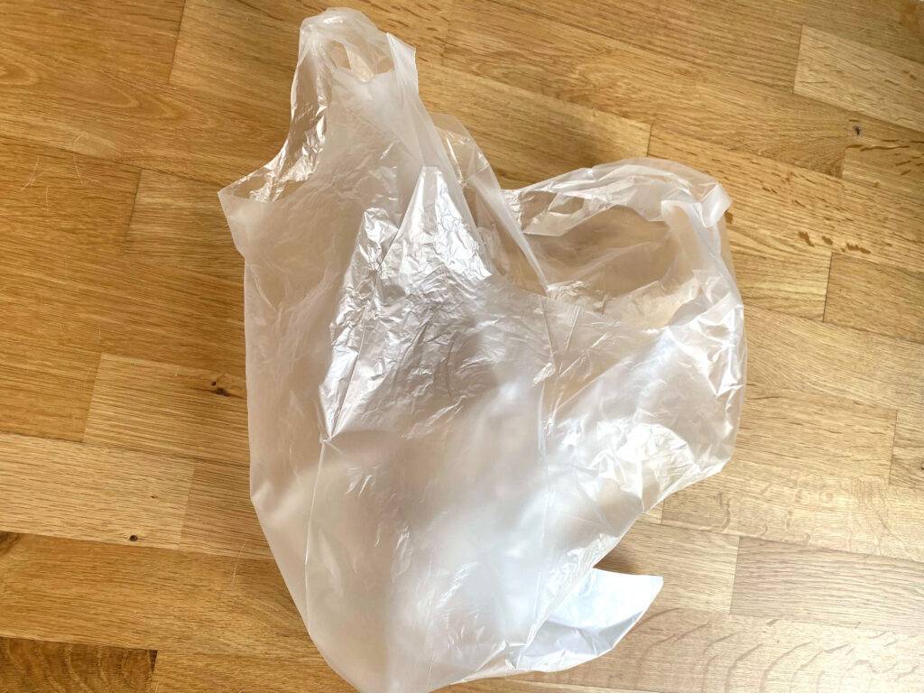 Ein transparenter Müllbeutel im Test liegt auf einem Parkettboden.
