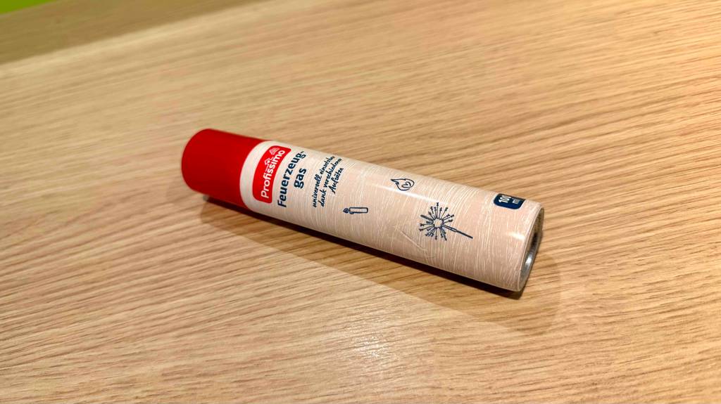 Eine Dose getestetes Feuerzeuggas liegt quer auf einer Holzfläche.