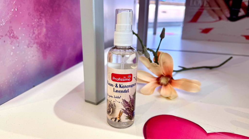 Kissenspray-Test: Eine Flasche mit Zerstäuber steht vor einer Blume auf einer weißen Fläche.