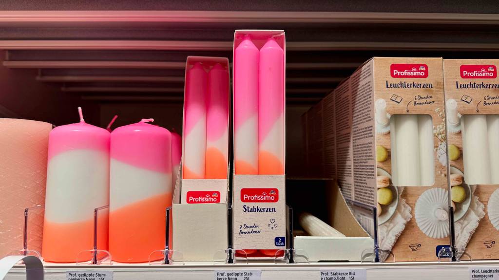 Stabkerzen im Test: Mehrere Packungen stehen zwischen anderen Kerzenarten in einem Regal.
