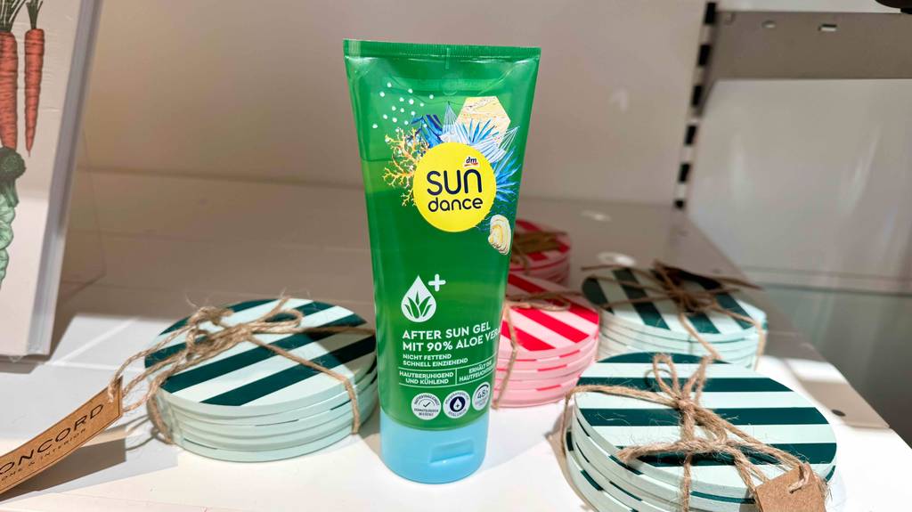 Eine Tube mit getestetem After Sun Aloe vera steht auf einem Regal mit Untersetzern für Gläser.