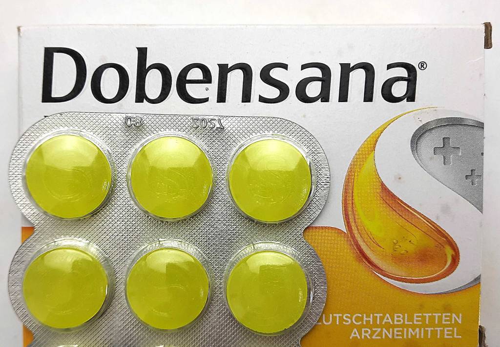 Die getesteten Erkältungsmedikamente in Form von gelben Lutschtabletten der Marke Dobensana liegen oberhalb ihrer Verpackung.