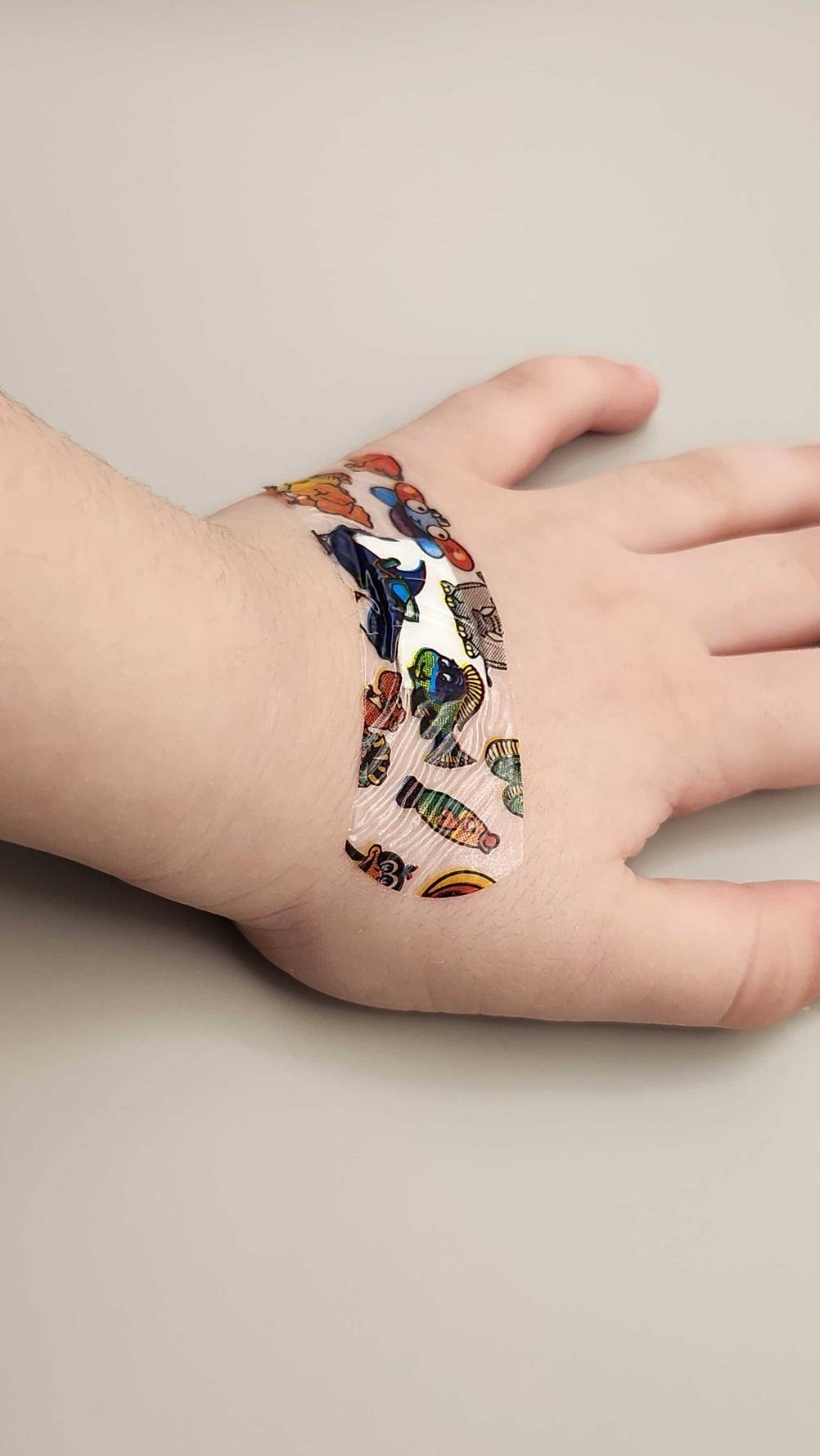 Ein getestetes Pflaster im Tierfiguren-Design klebt auf dem Handrücken einer Kinderhand.