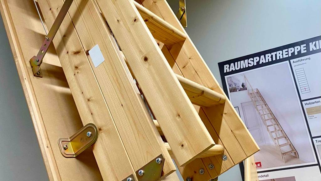 Nahaufnahme einer zusammengeschobenen Holz-Bodentreppe im Test, ausgestellt in einem Verkaufsbereich.