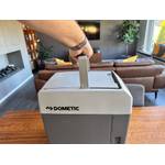 Eine Hand hält die Dometic TropiCool TC 21FL an ihrem Griff fest