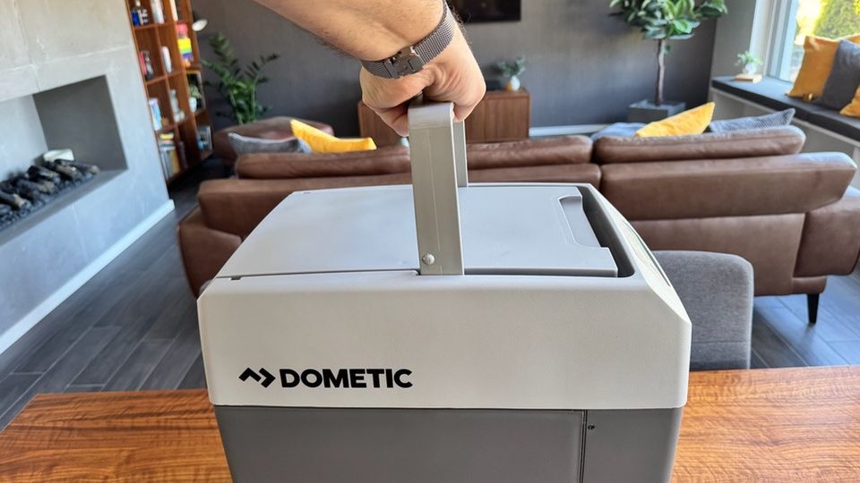 Eine Hand hält die Dometic TropiCool TC 21FL an ihrem Griff fest