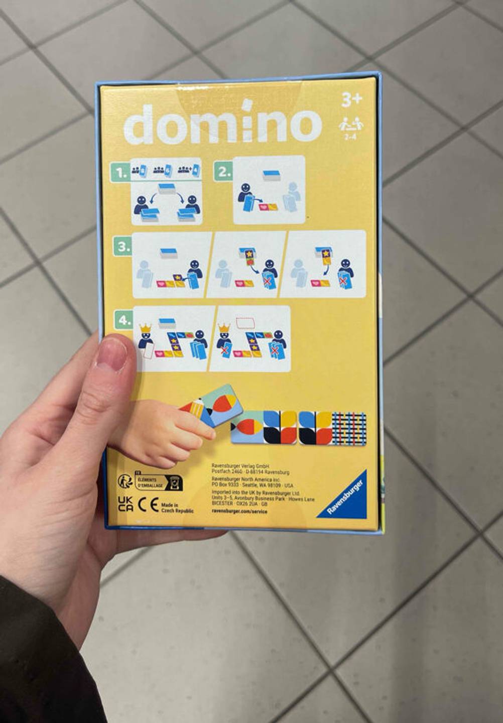 Eine Hand zeigt die Spieleanleitung auf der Rückseite der Verpackung mit dem Domino-Spiel im Test.