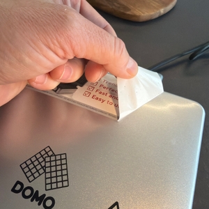 Eine Hand zieht einen Aufkleber vom Domo-Waffelautomat.