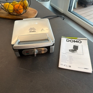 Der Lieferumfang vom Domo-Waffelautomat steht auf einer Arbeitsplatte.