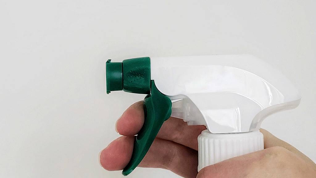 Hand betätigt den Sprühkopf einer Flasche