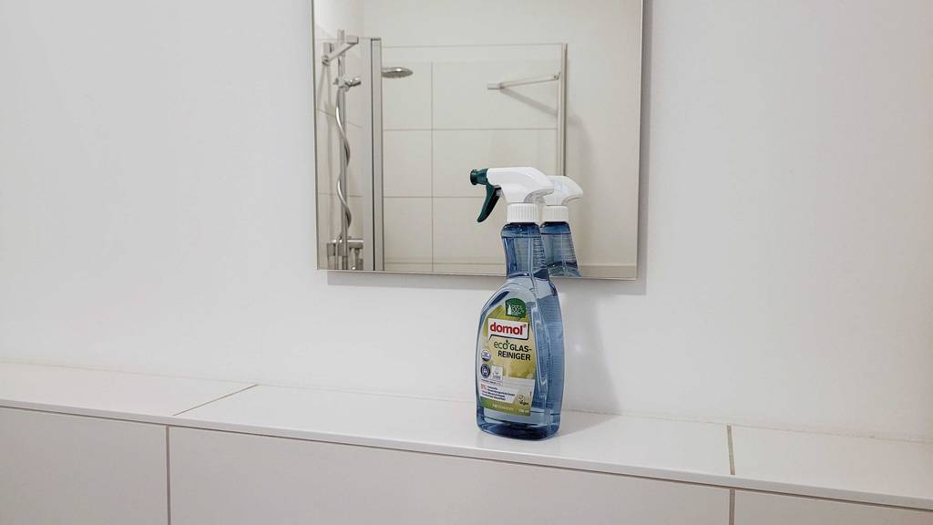Flasche Domol Glasreiniger vor einem Badezimmerspiegel