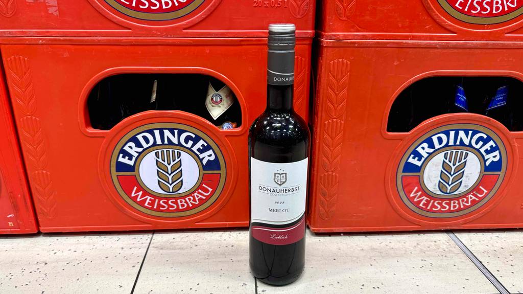 Eine Flasche getesteter Merlot steht vor Bierkisten.