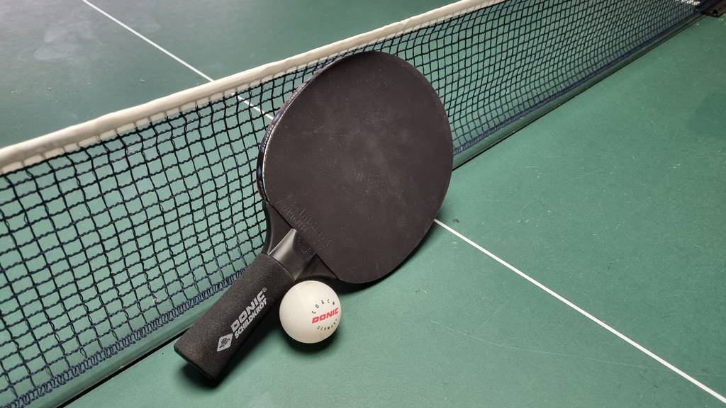 Tischtennisschläger-Test: Tischtennisschläger mit Ball auf einer Tischtennisplatte vor dem Netz