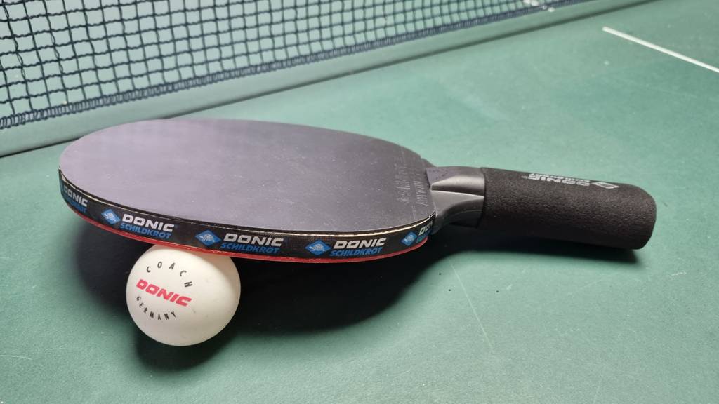 Tischtennisschläger-Test: Ein Tischtennisschläger auf der Platte liegend, darunter ein Tischtennisball.