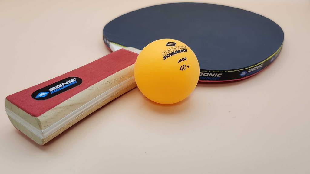 Tischtennisschläger im Test: Nahaufnahme eines liegenden Modells der Marke Donic Schildkröt neben einem gelben Tischtennisball.