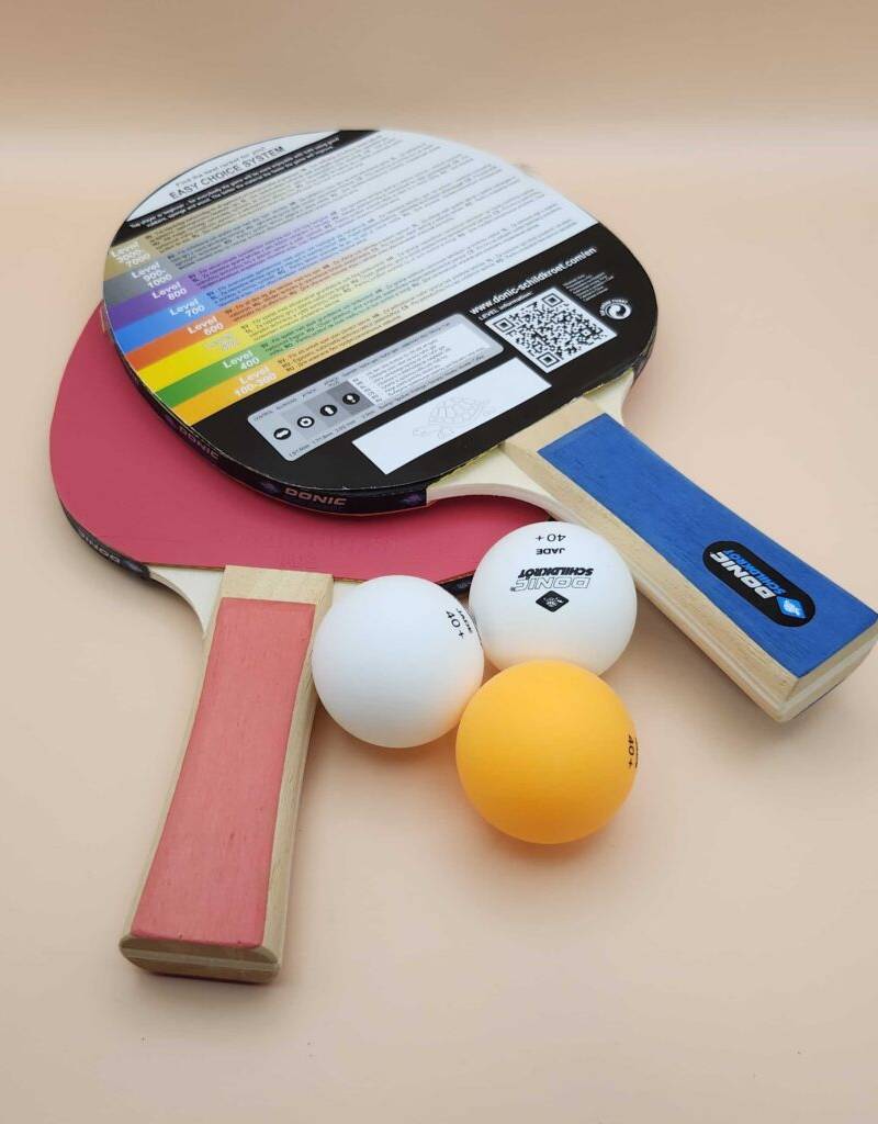 Tischtennisschläger im Test: Ein Zweier-Set liegt neben drei Tischtennisbällen auf einer beigefarbenen Oberfläche.