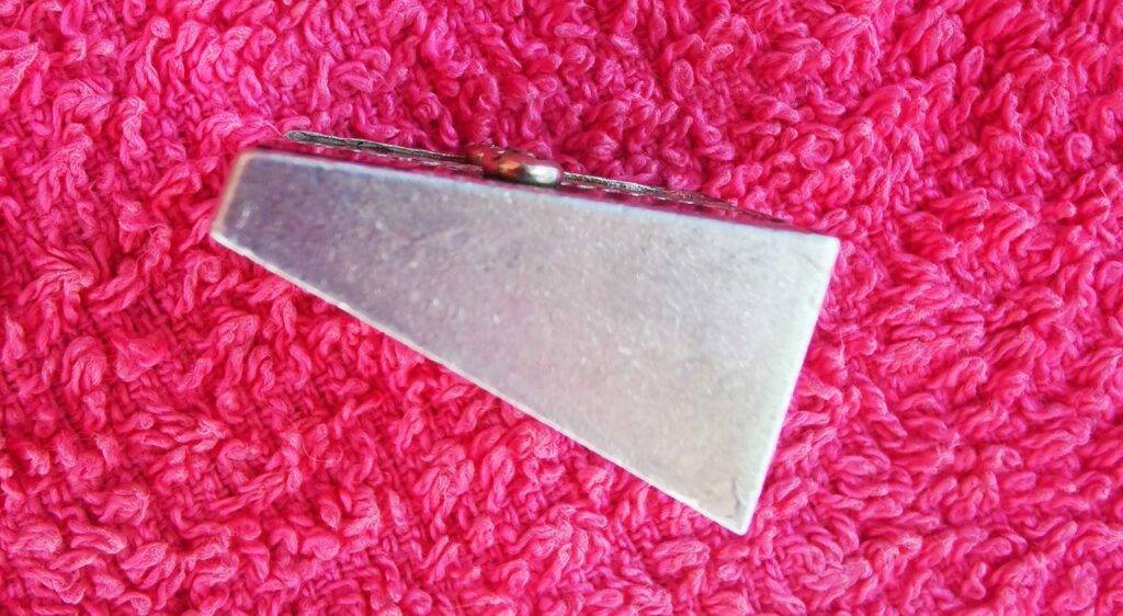 Der auf auf der Seite und einem roten Handtuch liegende, getestete Anspitzer aus Metall zeigt die aufgeschraubte Klinge.