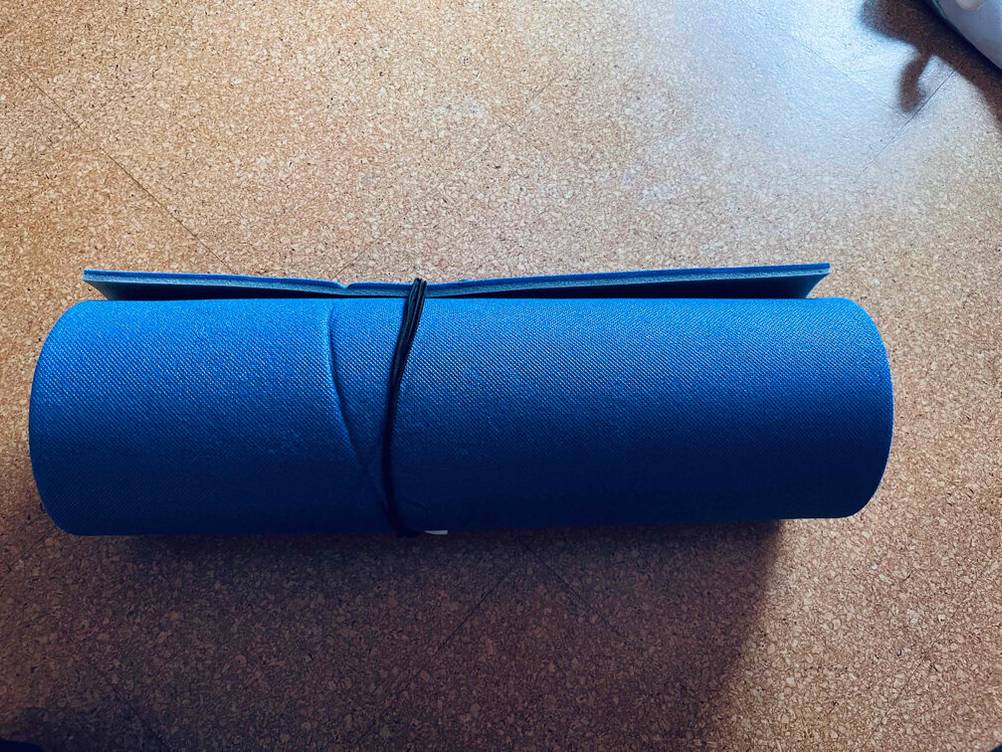 Eine gerollte und verschnürte Doppel-Isomatte im Test auf einem Boden liegend.