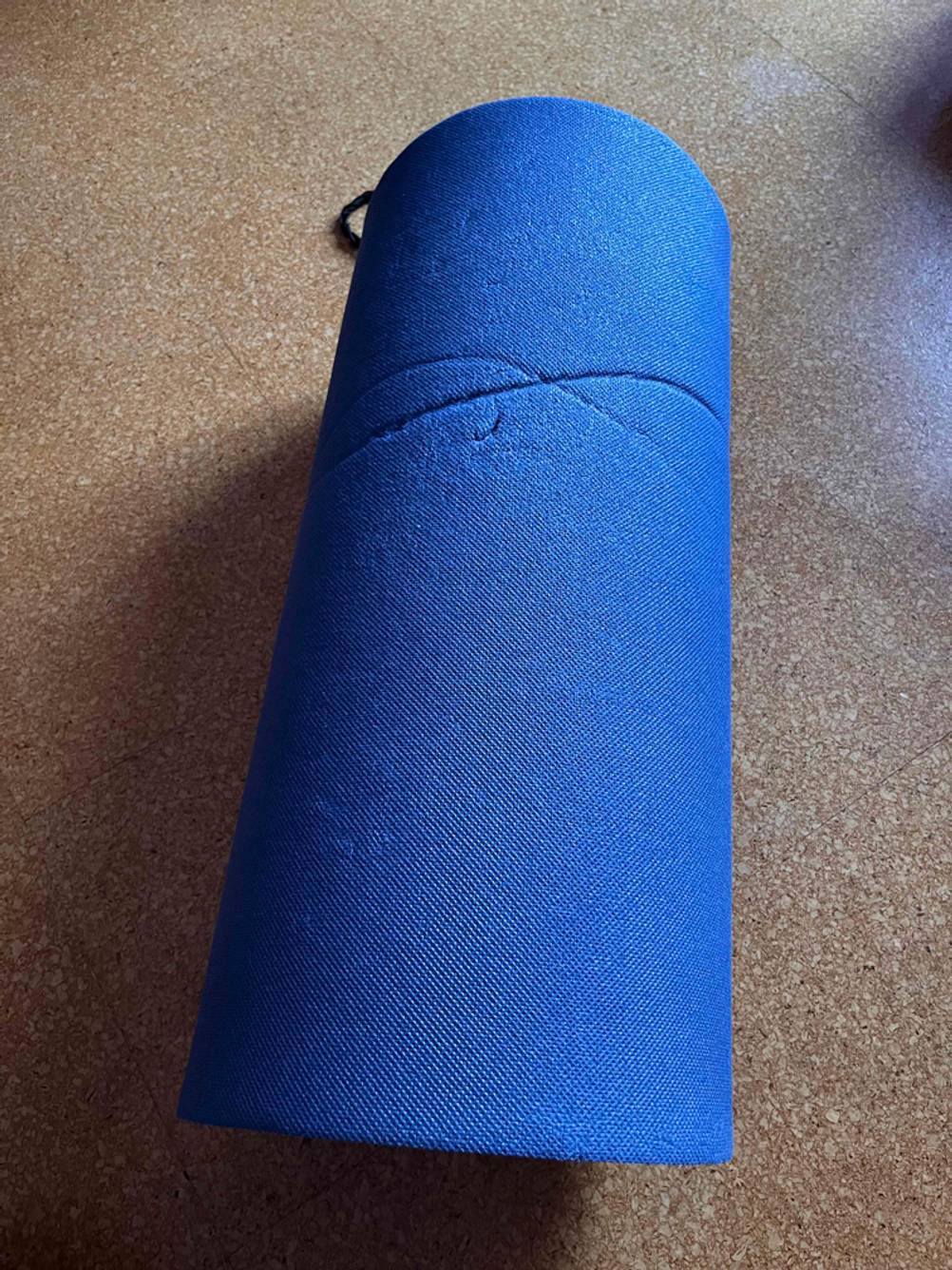 Eine getestete, zusammengerollte Doppel-Isomatte liegt auf einem Fliesenboden.