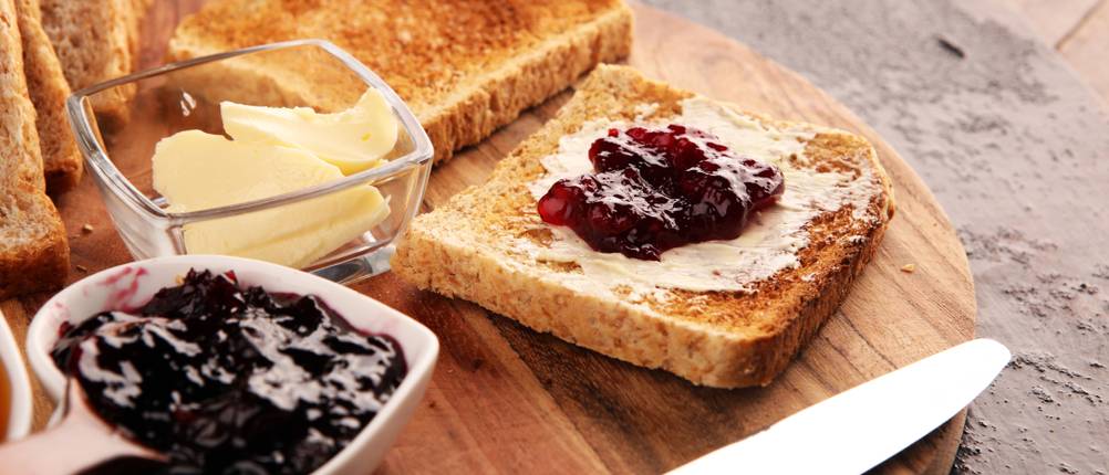 Doppel-Langschlitztoaster-Test: auf einem Holzbrett befinden sich mehrere Scheiben Toast mit Butter und Marmelade. 