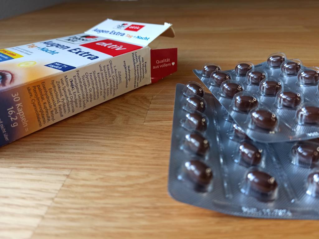 Blister mit dunklen Tabletten neben der Verpackung von Doppeherz 