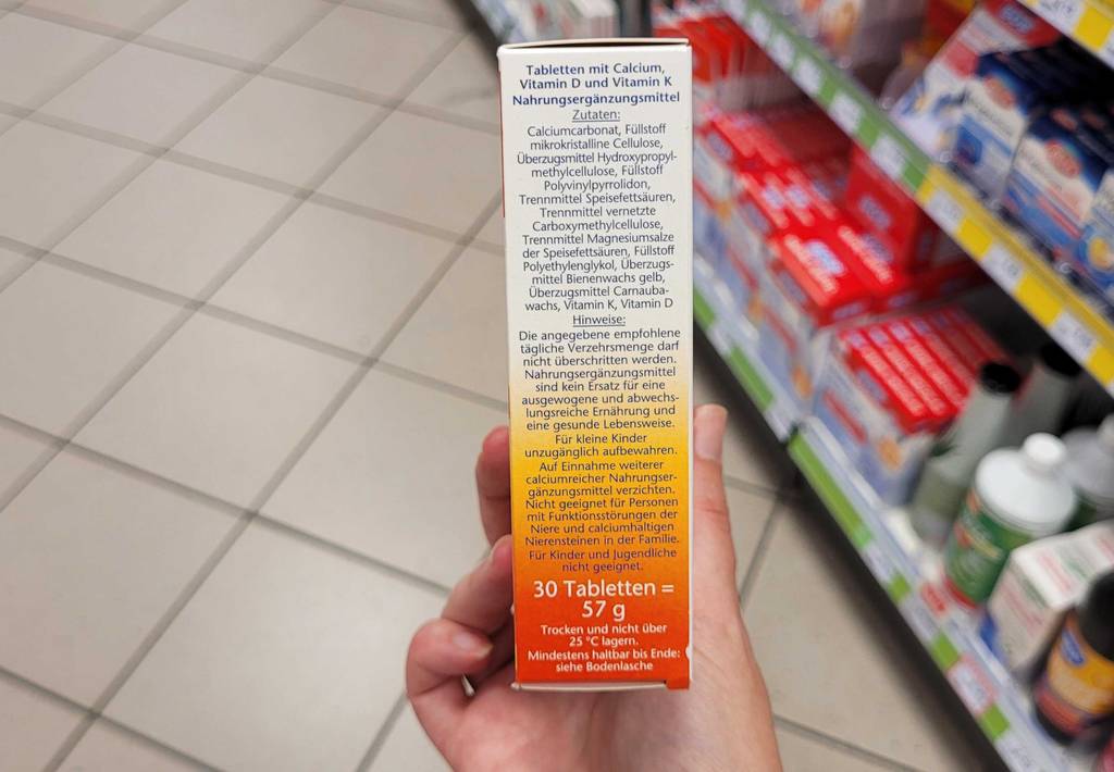 Eine Hand zeigt die Seite einer Packung getestetes Calcium, auf der Informationen zum Inhalt stehen.