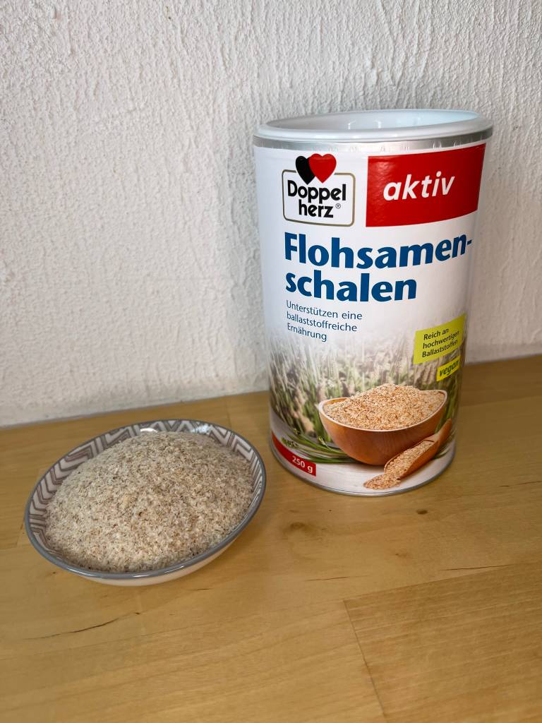 Eine Schale Flohsamen neben der Packung.