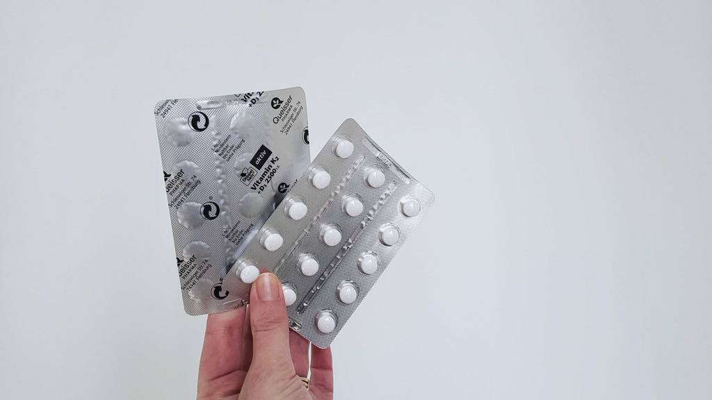 Vitamin-D-Tabletten-Test: Eine Hand hält zwei Blister, einer davon mit der Rückseite nach vorn.