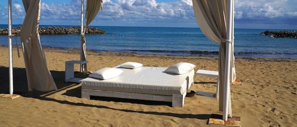 Doppelliege im Test: Ein weißes Doppelbett mit einem Baldachin steht am Strand.