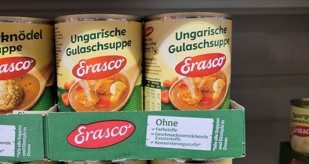 Mehrere Dosen des getesteten Dosengulasch in einem Karton in einem Regal.