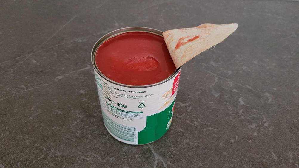 Seitenansicht einer geöffneten Verpackung der Dosentomaten im Test auf einer dunklen Fläche.