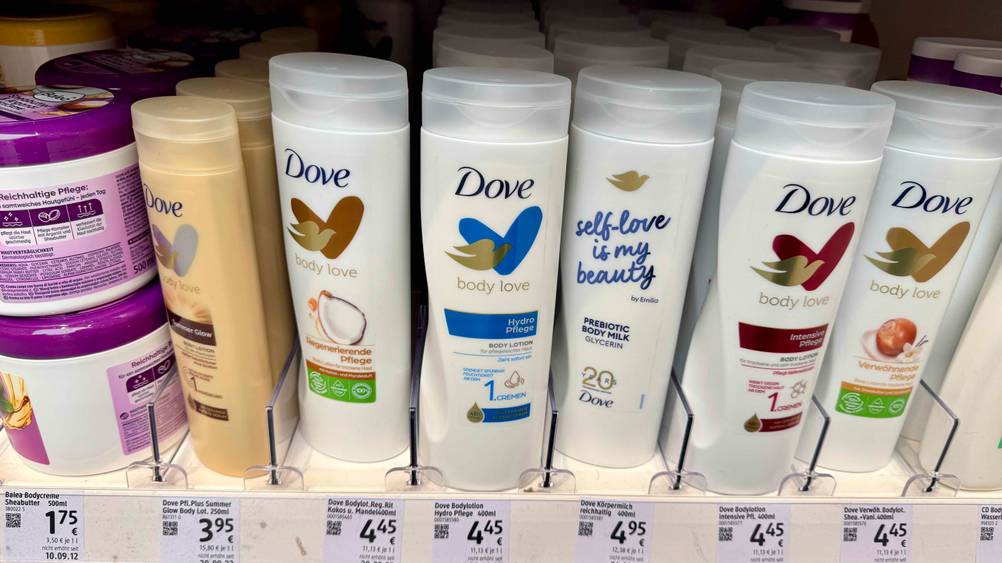 Mehrere Flaschen der getesteten Dove-Bodylotion stehen in einem Verkaufsregal neben anderen Produkten.