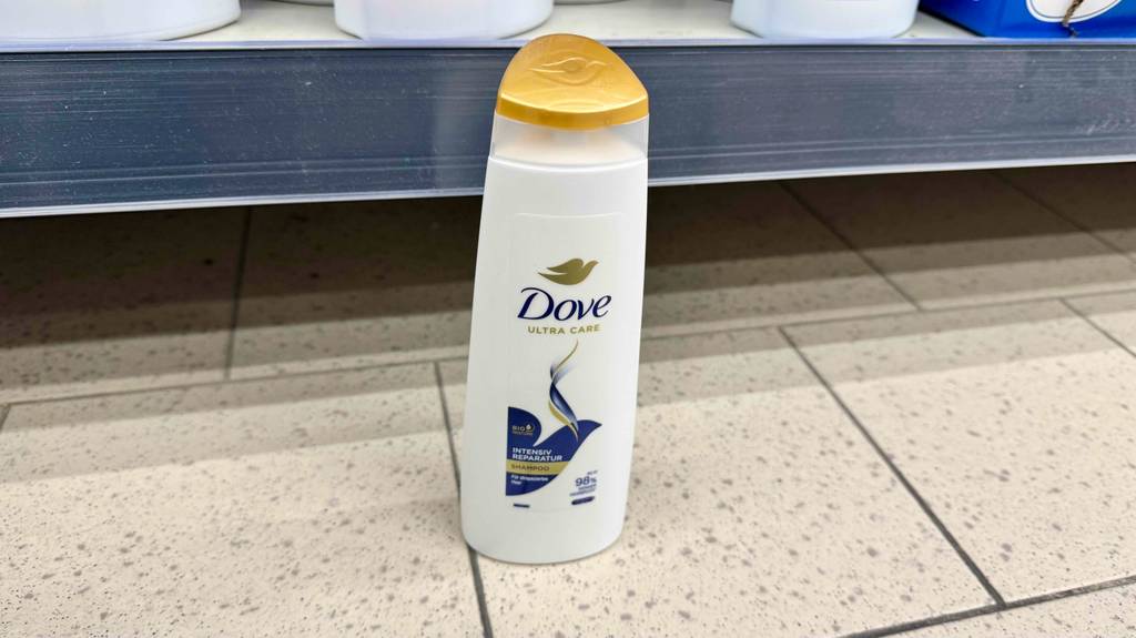 Im Test: Dove-Shampoo in der weißen Quetschflasche steht vor einem Regal auf dem Boden.