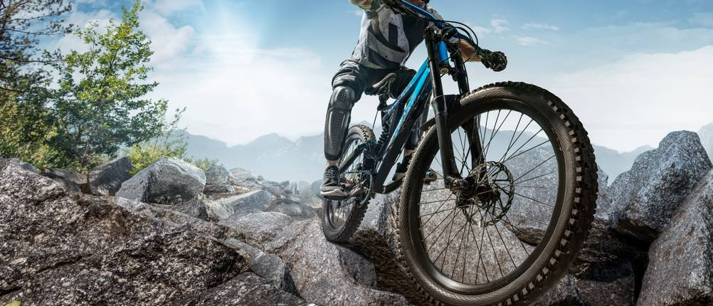 Downhill-Federgabel-Test: Downhill-Biker fährt in den Bergen über große Steine