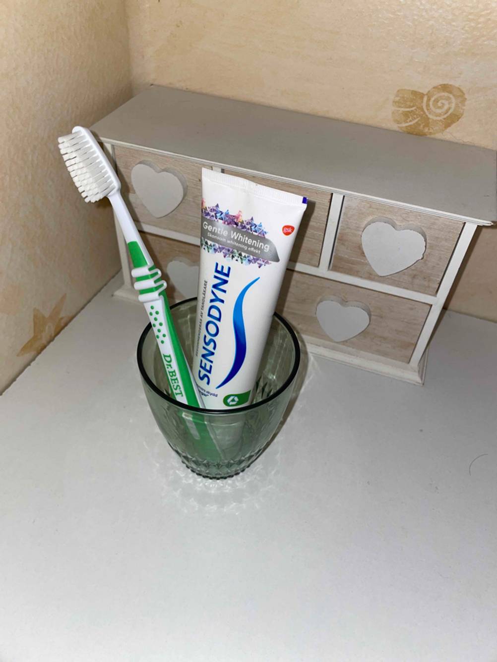 Dr. Best Zahnbürste mit Zahnpasta in einem Zahnputzbecher.